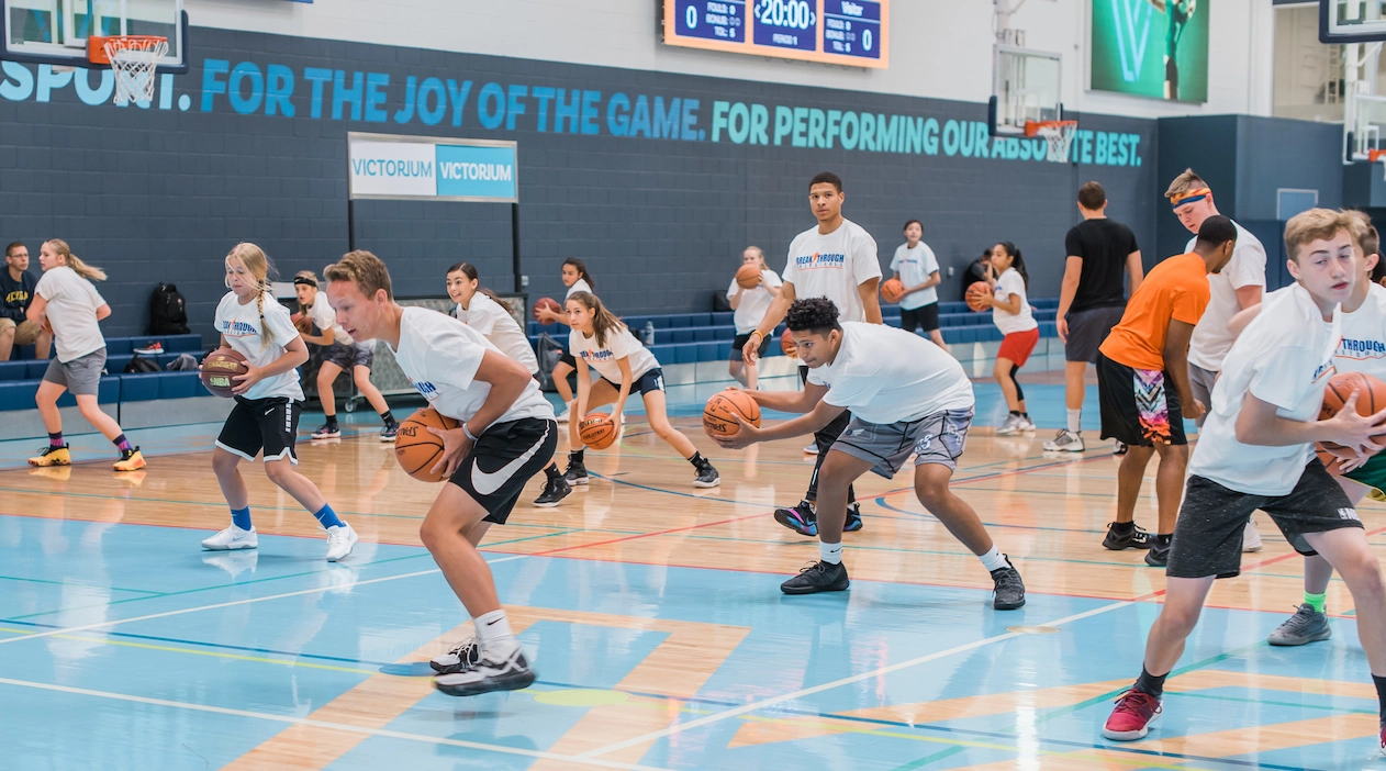 Group of young athletes playing basketball in a gym during a training session
