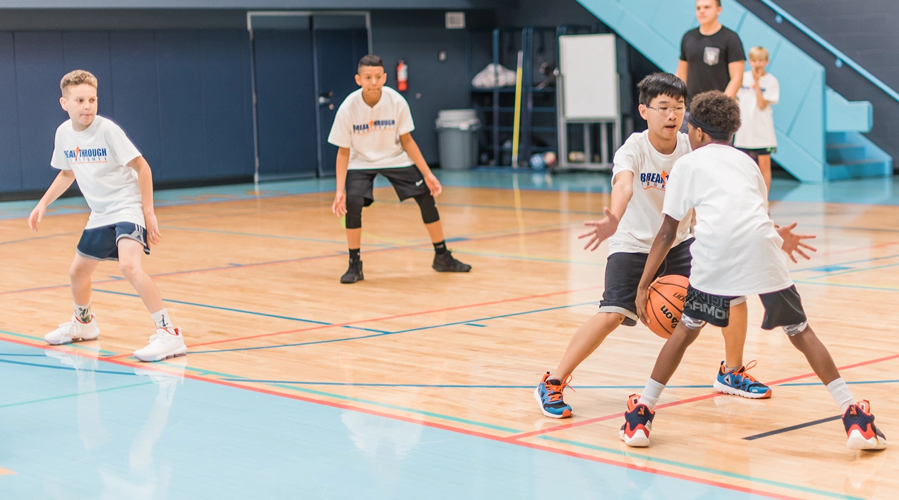 Group of young athletes playing basketball in a gym during a training session